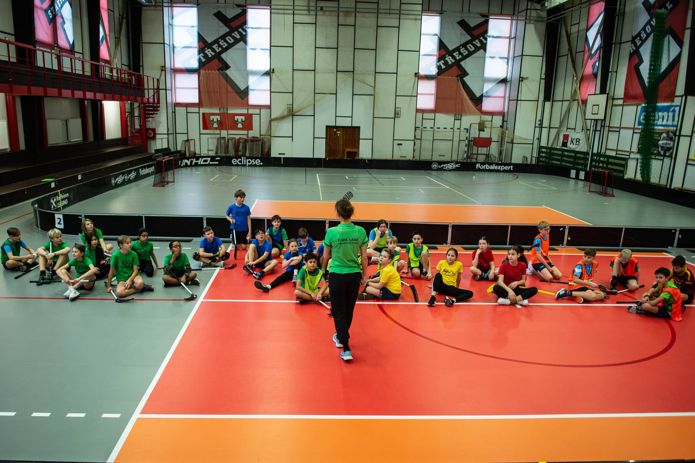 Primary children from Norbertov are listening to their PE Teacher Ms Lucie